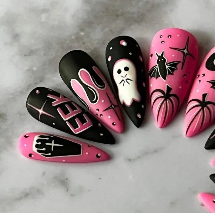 Ongles pointus rose et noir mats avec fantôme blanc, chauve-souris, citrouilles roses, étoiles, cercueil et coulures, sur marbre